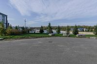 an empty parking lot with grass and shrubs on either side of the street and building