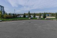 an empty parking lot with grass and shrubs on either side of the street and building