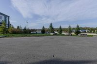 an empty parking lot with grass and shrubs on either side of the street and building