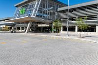 a grey building with a roof and glass windows that has a green sign in the front