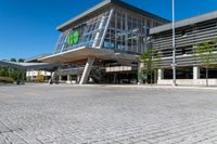 a grey building with a roof and glass windows that has a green sign in the front