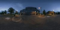 the intersection of a parking lot and an office building at night with street light and dark clouds in the background