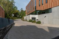 a concrete walkway between two buildings on the side of the road, and a stop sign