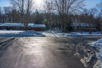 a house and trees are seen in the snow on this street intersection, in front of a wintery scene