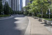 a car driving down an empty street lined with tall buildings and trees in the background