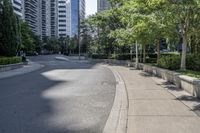 a car driving down an empty street lined with tall buildings and trees in the background