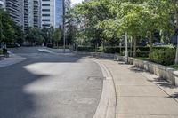 a car driving down an empty street lined with tall buildings and trees in the background