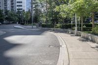 a car driving down an empty street lined with tall buildings and trees in the background