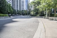 a car driving down an empty street lined with tall buildings and trees in the background