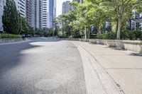 a car driving down an empty street lined with tall buildings and trees in the background