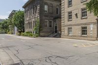 a street has some trees on each side and brick buildings in the background with a white and black sign on it