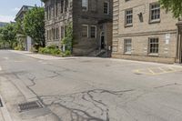 a street has some trees on each side and brick buildings in the background with a white and black sign on it