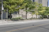 a street view with parking meters and trees in front of the building by the road