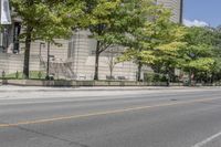 a street view with parking meters and trees in front of the building by the road