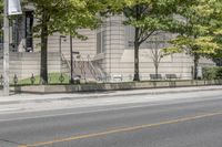 a street view with parking meters and trees in front of the building by the road