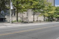 a street view with parking meters and trees in front of the building by the road