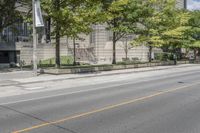 a street view with parking meters and trees in front of the building by the road