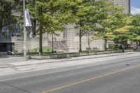 a street view with parking meters and trees in front of the building by the road