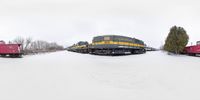 a group of trains on train tracks with a cloudy sky in the background and snow around them