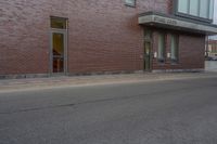 a woman walking down the sidewalk towards an entrance to a building in a large brick area