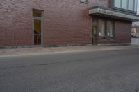 a woman walking down the sidewalk towards an entrance to a building in a large brick area