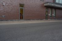 a woman walking down the sidewalk towards an entrance to a building in a large brick area