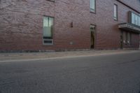 a woman walking down the sidewalk towards an entrance to a building in a large brick area