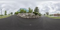 the building is made of large boulders on both sides of the road, near a sidewalk that splits into the grass