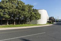 a large white structure sits next to a street corner, with trees in front of it