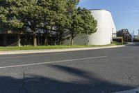 a large white structure sits next to a street corner, with trees in front of it