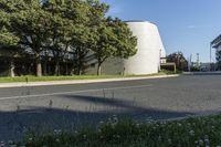 a large white structure sits next to a street corner, with trees in front of it