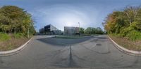 a 360 - view of the intersection with the sun shining over some buildings with trees in front