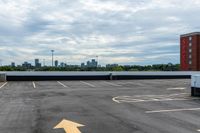 an empty parking lot with buildings in the background and two arrow signs pointing left to right