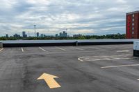 an empty parking lot with buildings in the background and two arrow signs pointing left to right