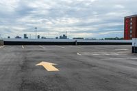 an empty parking lot with buildings in the background and two arrow signs pointing left to right