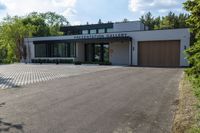 a building has a garage and sidewalk in front of it to the side, a large car sits parked on the side