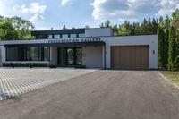 a building has a garage and sidewalk in front of it to the side, a large car sits parked on the side