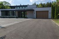 a building has a garage and sidewalk in front of it to the side, a large car sits parked on the side