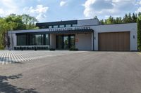 a building has a garage and sidewalk in front of it to the side, a large car sits parked on the side