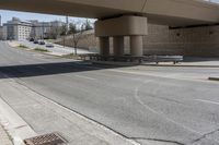 a street underpass with cars driving under it and buildings behind it with an overpass