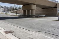 a street underpass with cars driving under it and buildings behind it with an overpass