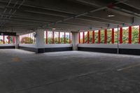 an empty parking garage has large windows, bright red curtains on the window panels and white concrete flooring