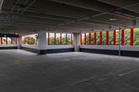 an empty parking garage has large windows, bright red curtains on the window panels and white concrete flooring