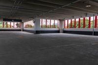 an empty parking garage has large windows, bright red curtains on the window panels and white concrete flooring