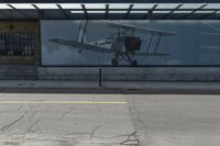 a bus stop on the side of a building next to a parking lot with a plane in it