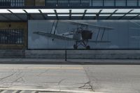 a bus stop on the side of a building next to a parking lot with a plane in it