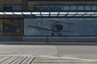 a bus stop on the side of a building next to a parking lot with a plane in it