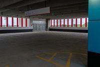 an empty parking garage with red and white striped windows over concrete floors and floor tiles