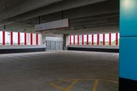 an empty parking garage with red and white striped windows over concrete floors and floor tiles