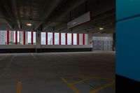 an empty parking garage with red and white striped windows over concrete floors and floor tiles